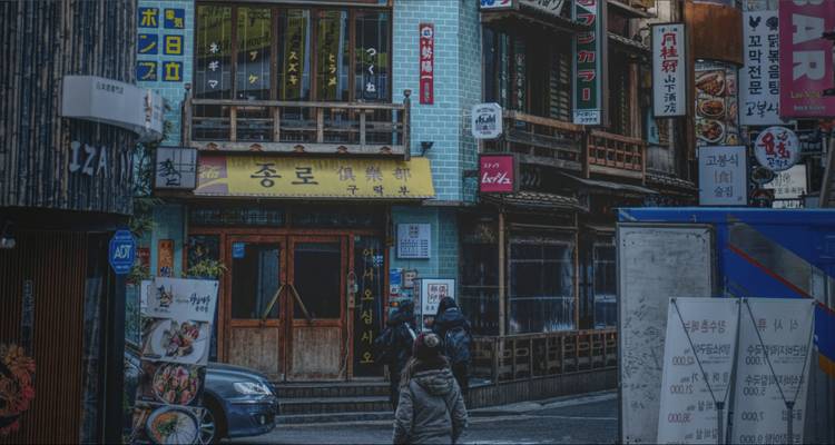 Coin de rue d'ambiance mélancolique avec signalétique faible et deux piétons au crépuscule.