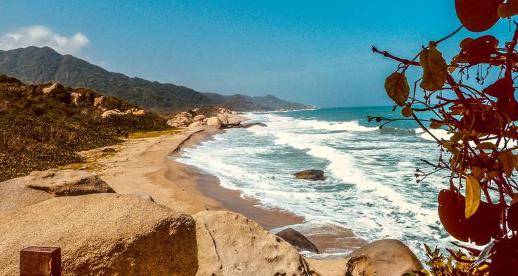 Paisaje costero con olas rompientes y una playa de arena.
