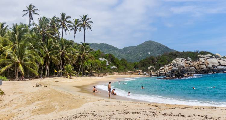 Escena de playa con gente relajándose y nadando.