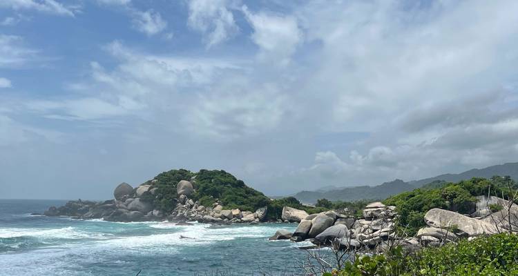 Acantilado rocoso cubierto de vegetación verde con olas estrellándose contra la costa del Caribe.