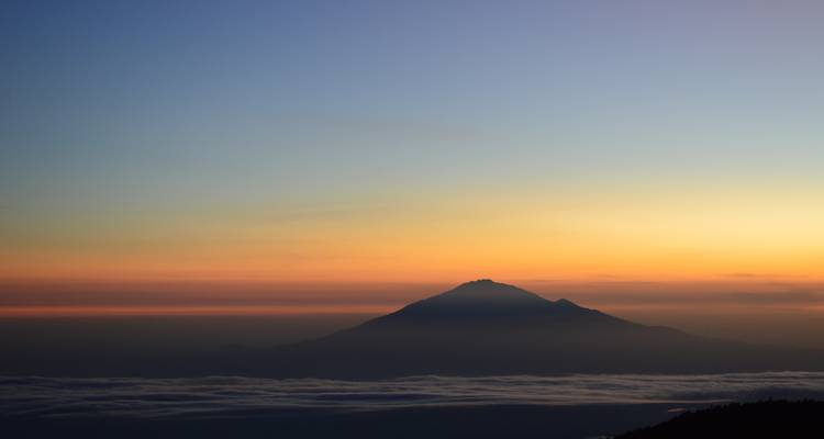Paisaje del amanecer con una silueta de montaña.
