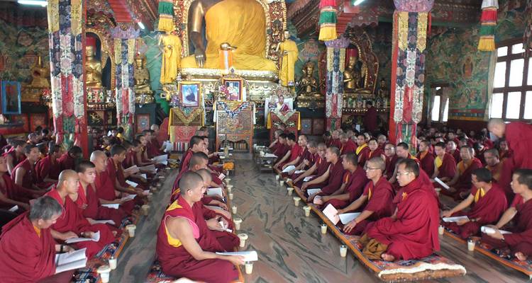 Monniken zittend in een kleurrijke tempelzaal tijdens een ceremonie.