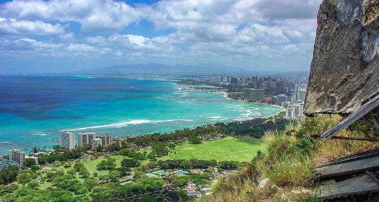 Panoramic view from a cliff overlooking a city and ocean with blue waters.