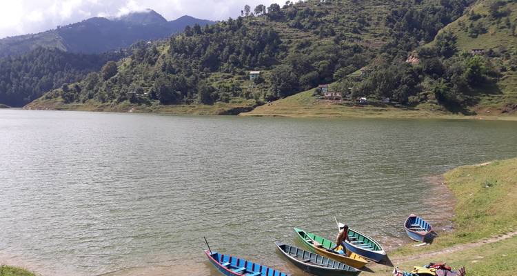 Los coloridos botes de remos de madera descansan en la orilla cubierta de pasto de un tranquilo lago de montaña.