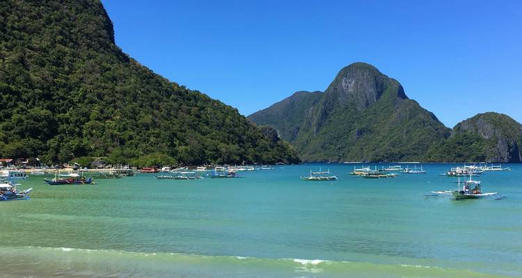 Une baie avec des bateaux traditionnels et des montagnes luxuriantes en arrière-plan.