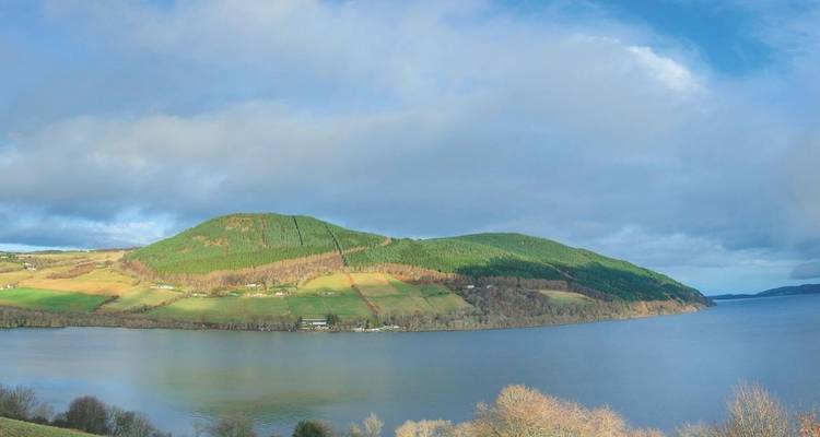 Vue panoramique d'un lac et de montagnes sous un ciel bleu.
