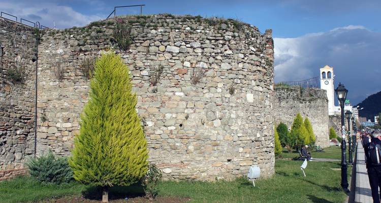 Steinerne Festungsmauern in einem historischen Bereich mit einem Uhrenturm.