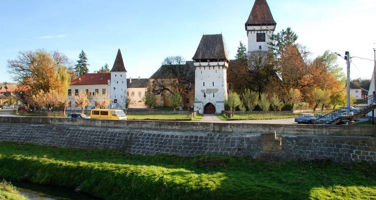 Historische Gebäude mit Türmen und einer Steinmauer in einer Kleinstadt.