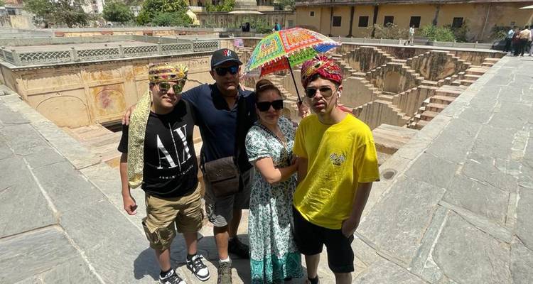 Groupe de touristes posant près d'un puits à degrés ancien.