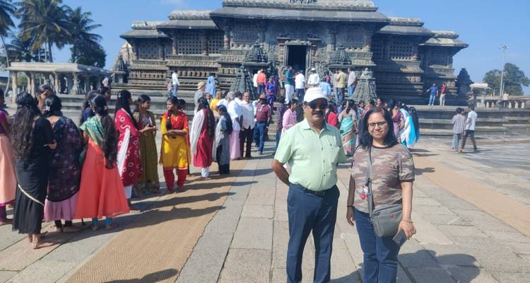 Des touristes posant devant un temple ancien aux sculptures complexes.