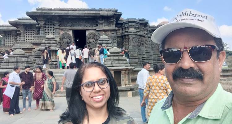 Des touristes prenant un selfie devant un temple en pierre détaillé.