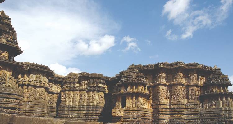 Extérieur d'un temple ancien richement sculpté sous un ciel bleu.