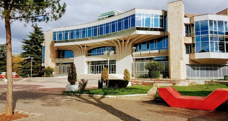 Moderne gebouw met glazen ramen en een rood sculptuur ervoor