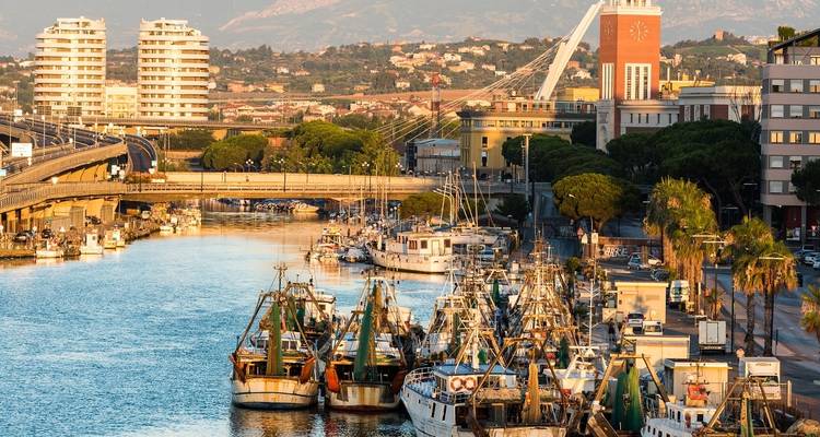 Vissersboten in een haven bij zonsondergang met bergen op de achtergrond