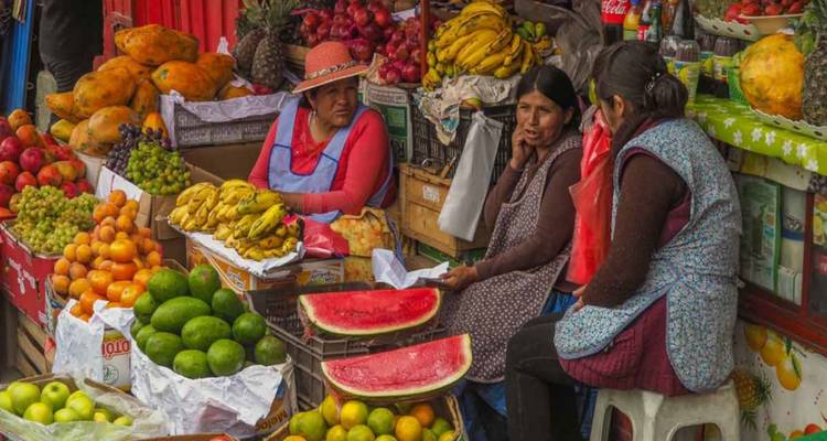 Vrouwen die kleurrijke vruchten en watermeloenen verkopen op een openluchtgroentemarkt.