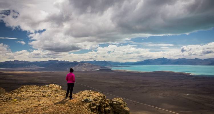 Person overlooking a vast landscape with a lake.