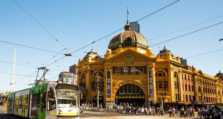 Flinders Street Station in Melbourne vol met mensen en een tram.