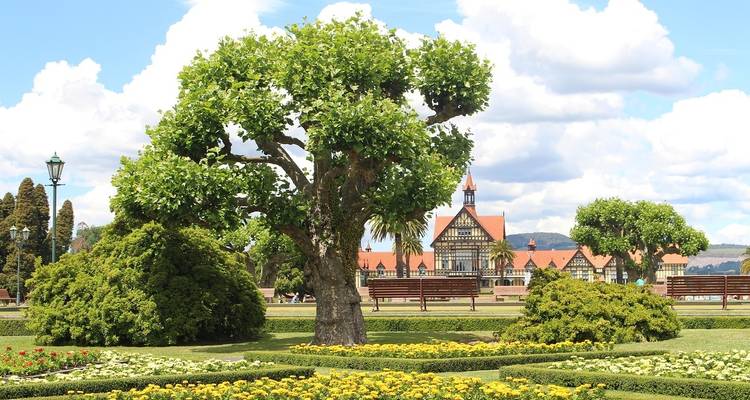 Garden with large trees and a historic building in Rotorua.