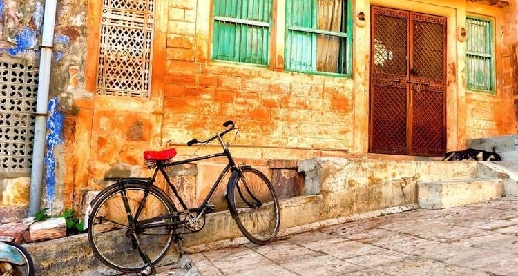Escena callejera con una bicicleta y una pared texturizada con puertas y ventanas.