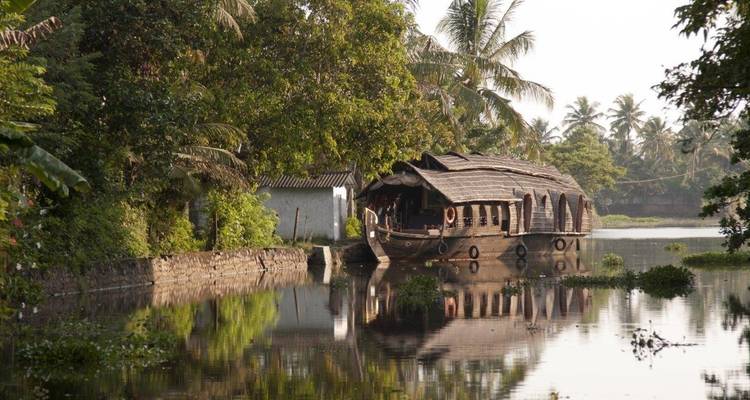 Casa flotante tradicional en un canal tranquilo rodeada de follaje.