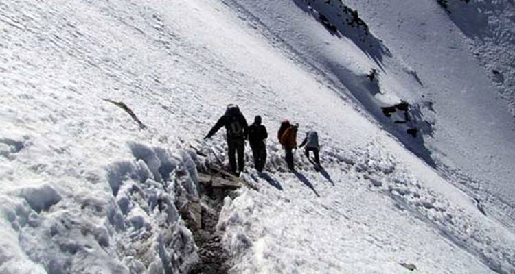 Wandelaars op een besneeuwde berghellingpad met fel zonlicht.