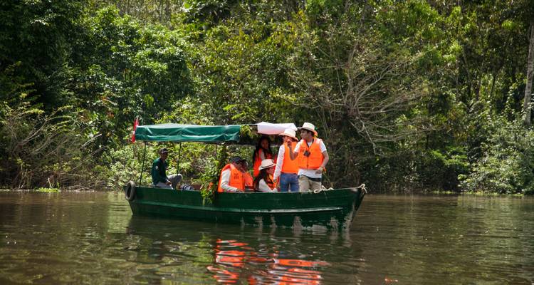 Gente en un bote en un río rodeado de bosque denso.