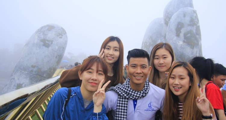 Group of friends posing on a bridge with stone sculptures.