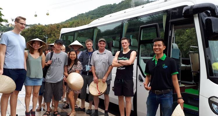 Group standing in front of a tour bus with mountains in the background.