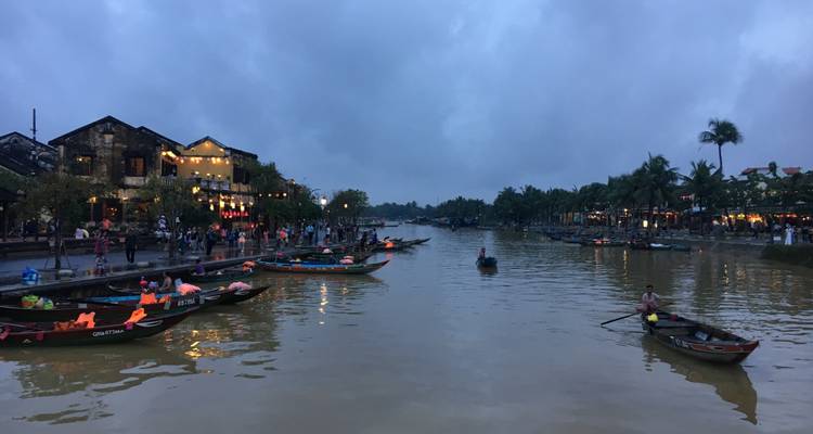 River with boats and buildings under a cloudy sky.