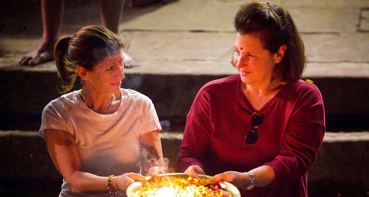 Dos mujeres sosteniendo una bandeja decorada, mirándose la una a la otra.