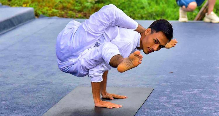 Hombre haciendo una pose de yoga compleja al aire libre.