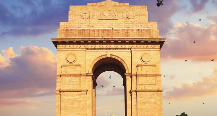 Monumentale boog tegen een kleurrijke hemel met vliegende vogels.