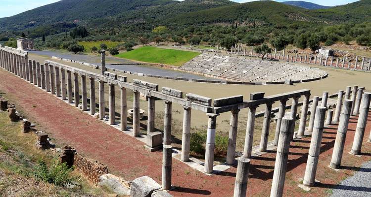 Ancient theater ruins with columns and a view of mountains.