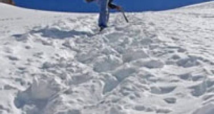 Persoon die op sneeuw loopt met klimuitrusting.