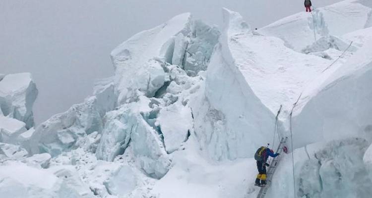 Klimmers op besneeuwde ijsformaties die ladders gebruiken.