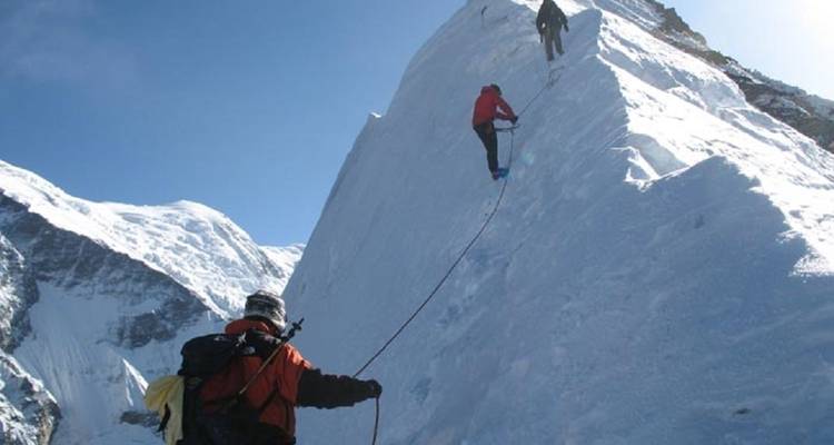 Gruppe von Bergsteigern, die einen steilen schneebedeckten Grat erklimmen.