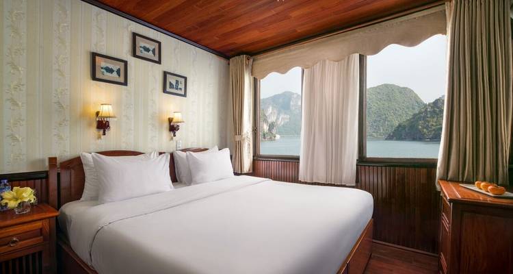 Innenraum einer Hütte mit Blick auf eine Bucht durch große Fenster.