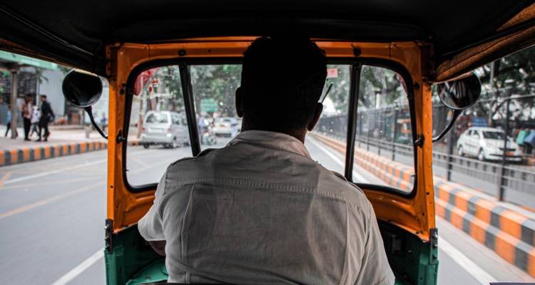 Interieur uitzicht vanaf de achterkant van een autorikshaw in een stedelijke omgeving.