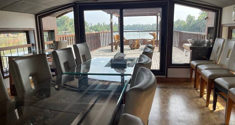 Interieur van een boot met eetruimte en grote ramen die uitkijken op het water.