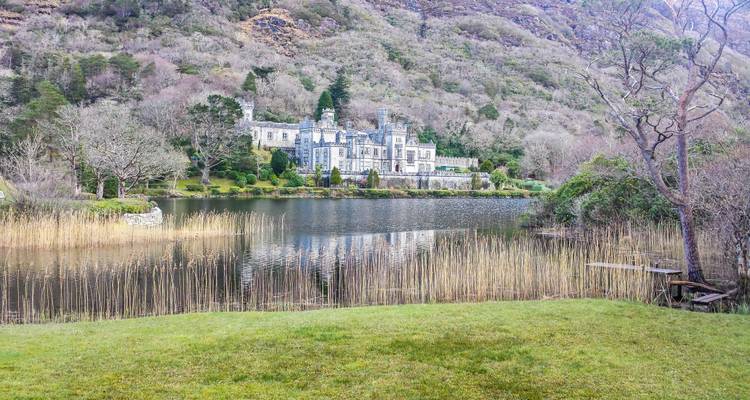 Bâtiment semblable à un château se reflétant dans un lac serein avec un arrière-plan montagneux.