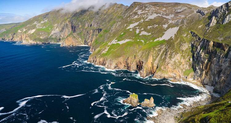 Falaises spectaculaires au bord de l'océan avec des vagues qui se brisent en contrebas.