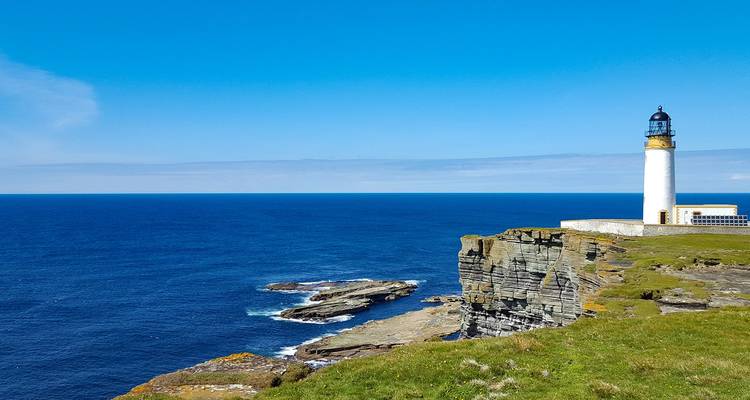 Lighthouse on a cliffside overlooking the ocean on a clear day.