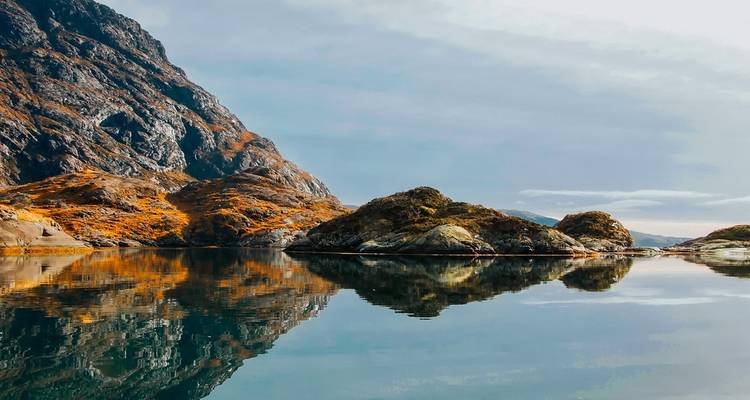 Reflets des montagnes et du ciel dans un lac calme.
