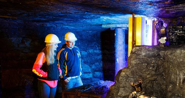 Deux personnes portant des casques de sécurité explorant un espace souterrain.