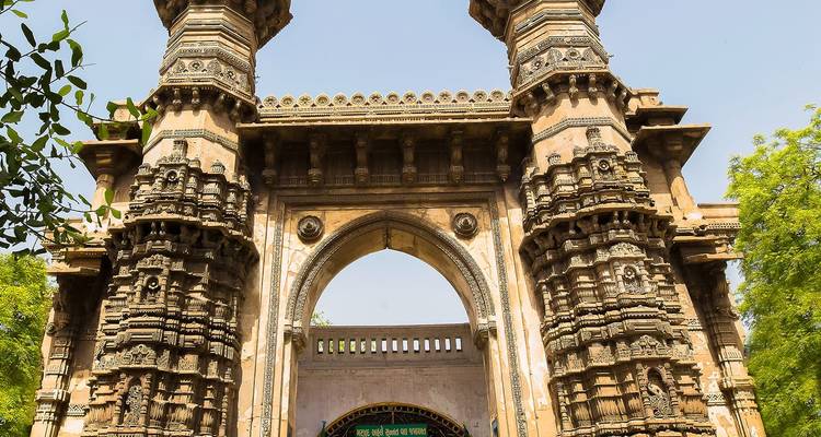 Aufwendiges Eingangstor mit kunstvollen Schnitzereien in einem Garten.