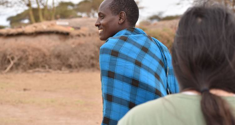 Person, die ein blau kariertes Kleidungsstück trägt, mit Bäumen im Hintergrund.