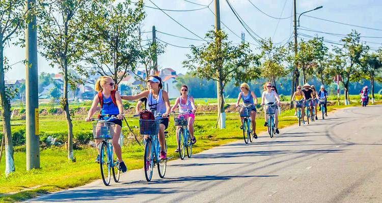 Groep mensen die fietsen langs een weg omringd door groen.