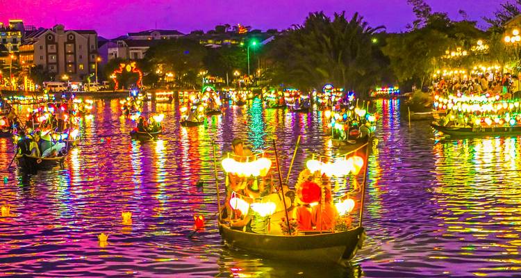 Rivierscène in de nacht met boten verlicht door kleurrijke lantaarns.