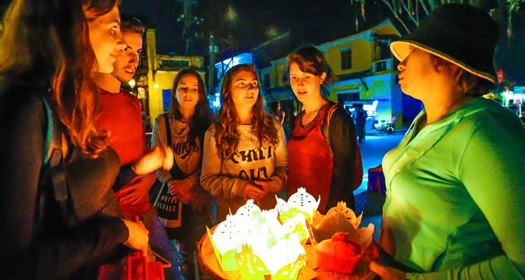 Groep mensen verzameld rond lantaarns 's nachts.