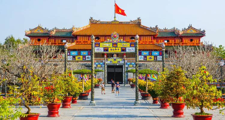 Historical gate with vibrant decor and people walking around.